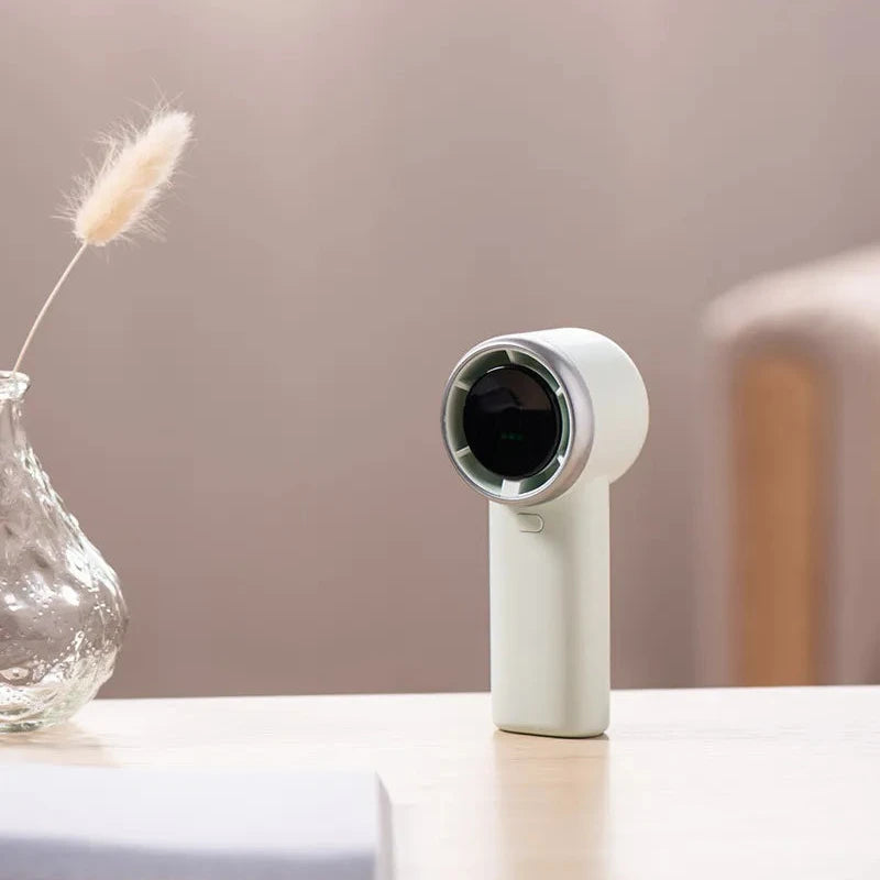 White handheld device on a table with a vase and plant in the background